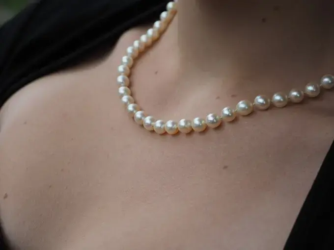 A close up of a woman wearing a pearl necklace.
