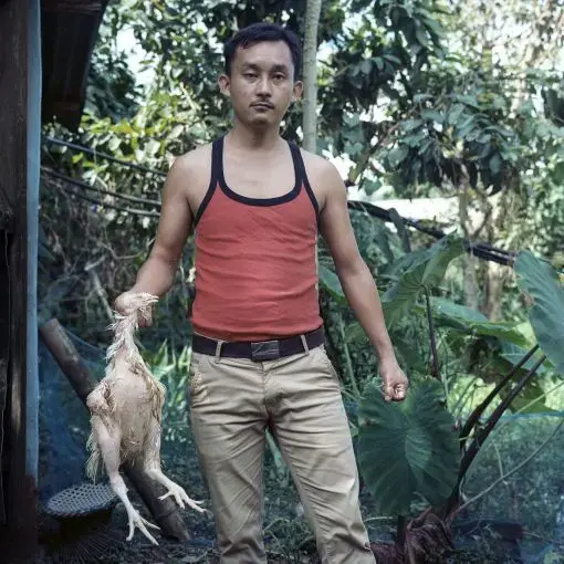 Salam Enao Meitei, 30. Thanga Tongbram Leikai, Manipur Salam Enao Meitei, a poultry owner, poses for a portrait while preparing a meal for a luncheon. The younger generation in communities surrounding Loktak is moving away from the traditional livelihood of fishing because making a living from fishing has becoming challenging. The older generation has been encouraging the younger generation to get an education to find a different means of livelihood.