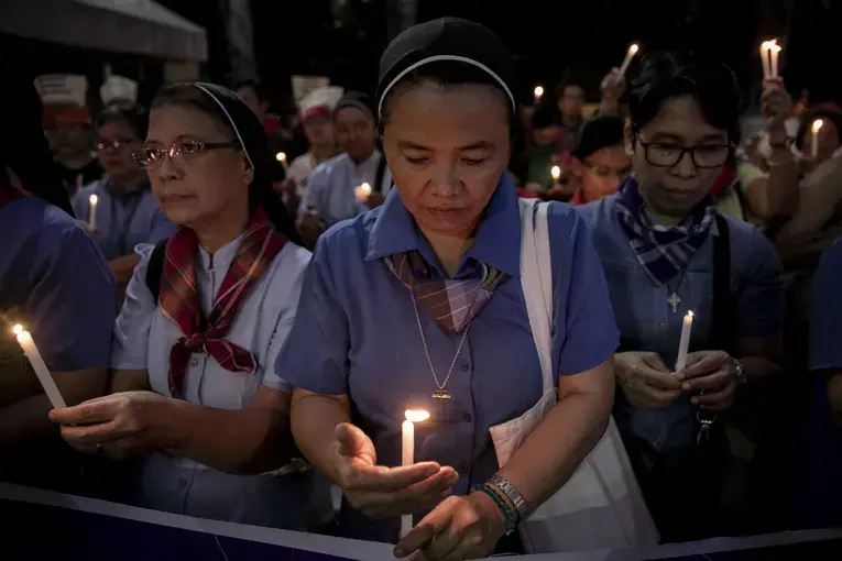 Nuns light their candles during a demonstration calling for