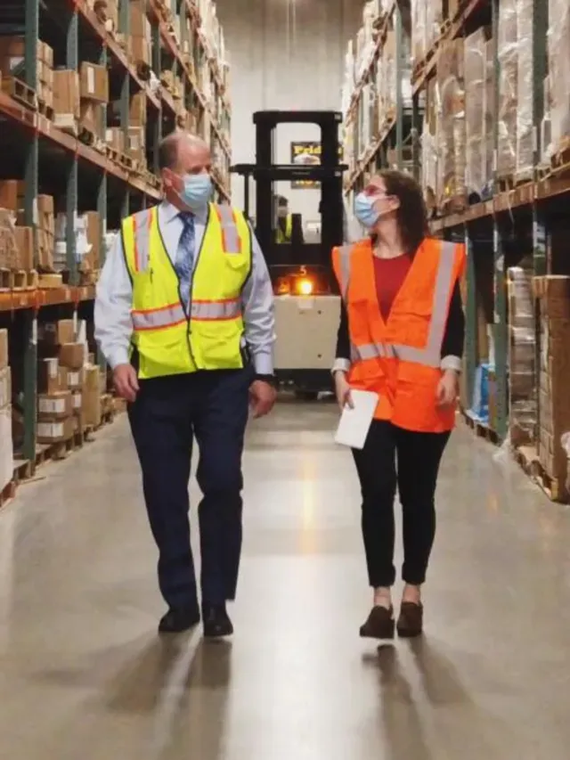 Two people wearing masks, walking in a warehouse
