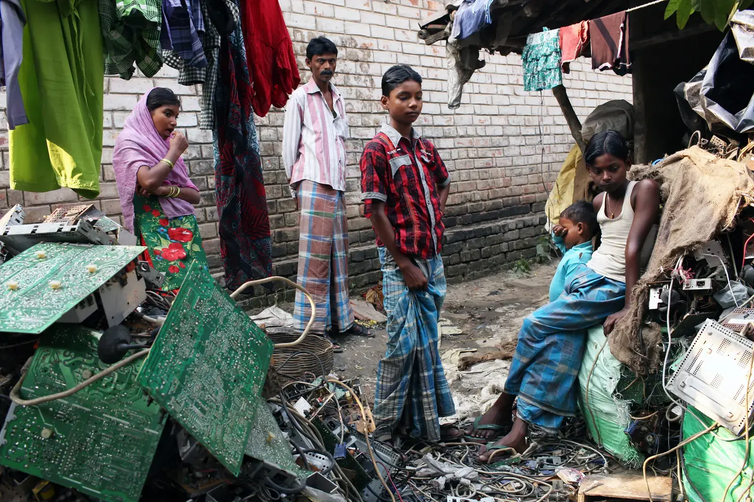 Villagers stand among piles of e-waste in the village of Sangrampur, located south of Kolkata in northeast India. Globally, an estimated 50 million tons of e-waste are produced annually, and much of it ends up in countries like India. Image by Sean Gallagher. India, 2013. Media file: e-waste-gallagher-01.jpg