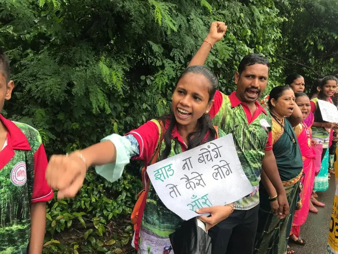 A young girl holds a handwritten sign in protest with other people
