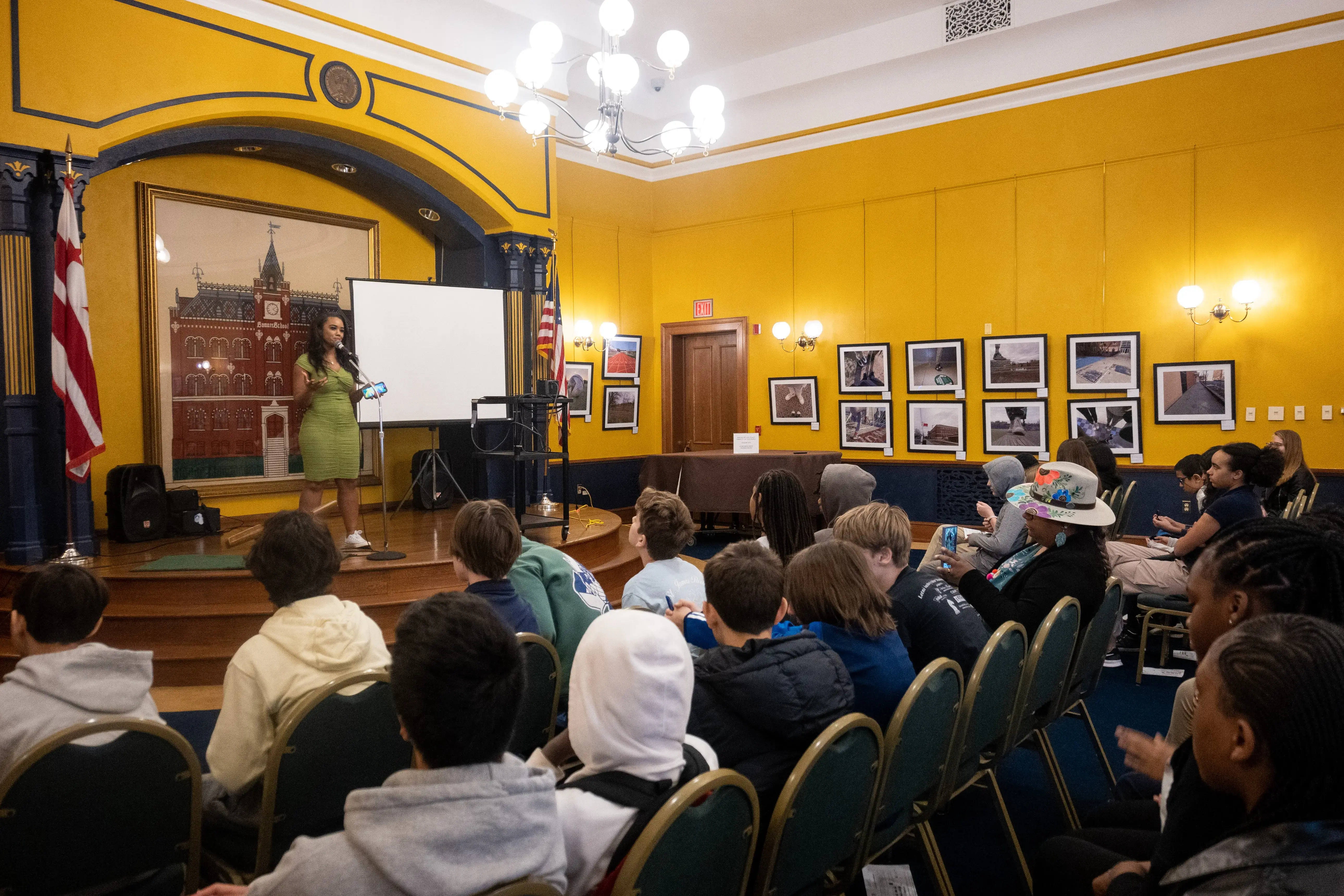 Pulitzer Center grantee Ashonti Ford stands on a stage in front of an audience of middle school students