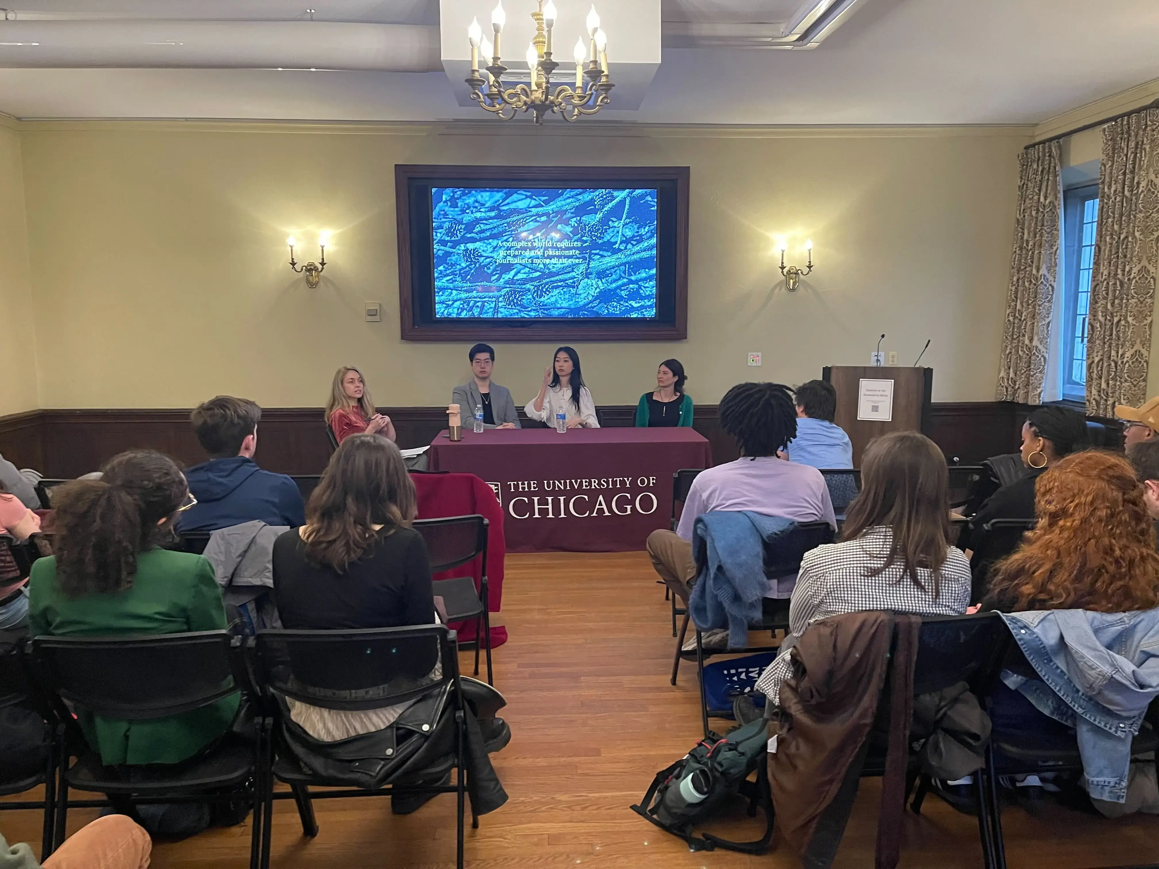Three people at a table with a presentation screen