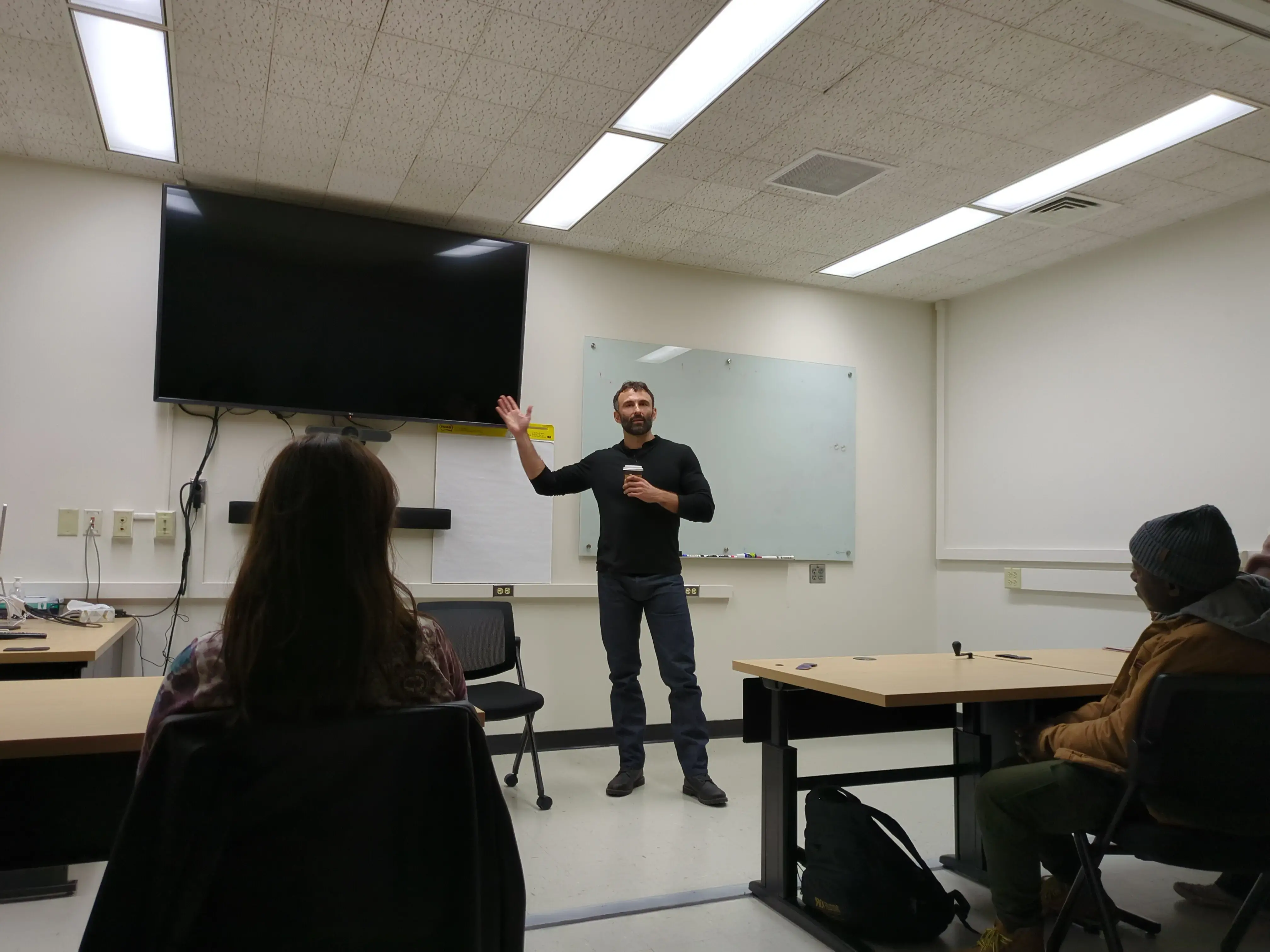 A man in front of a classroom with his armed raised.