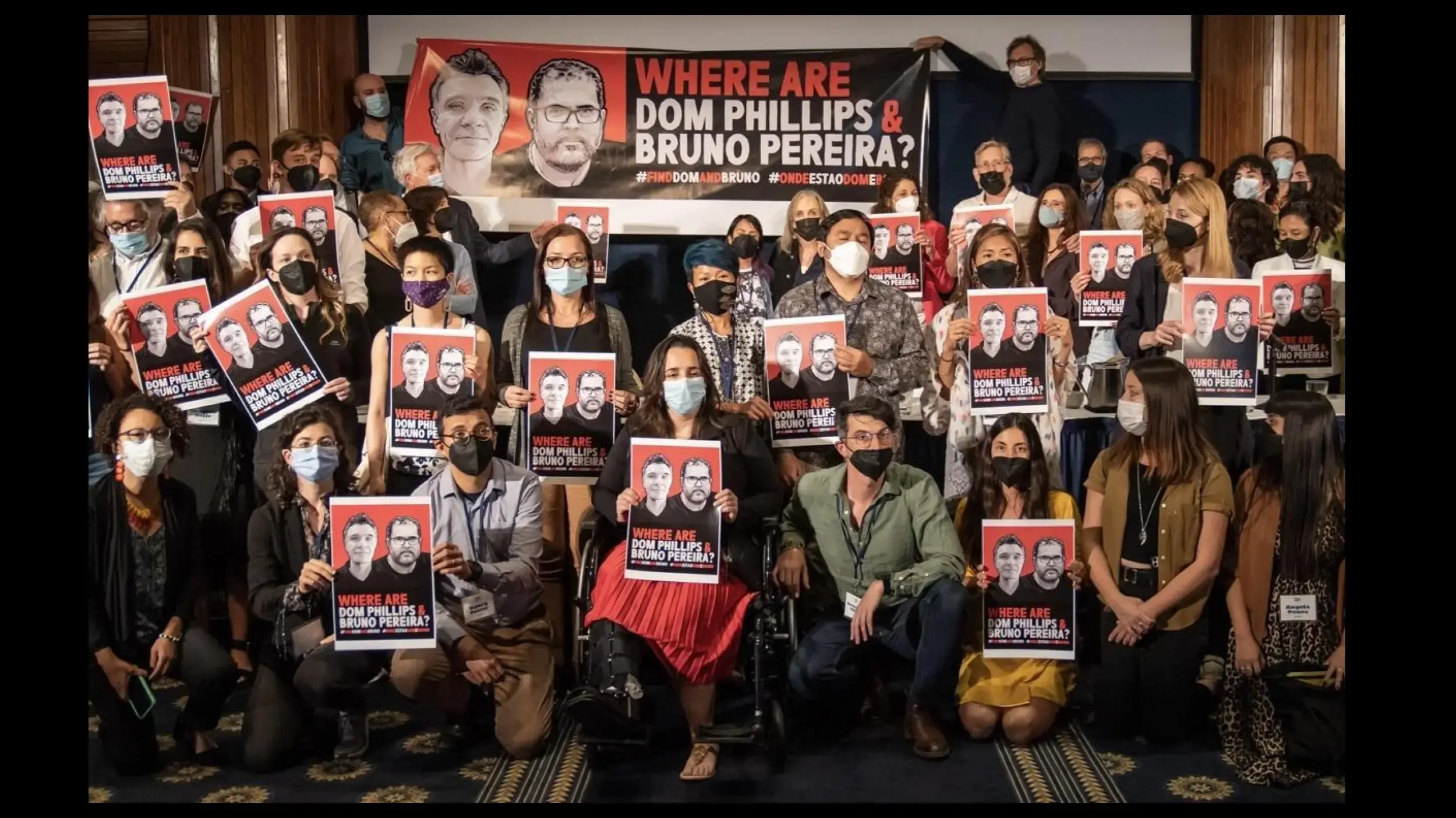 Pulitzer Center staff hold signs calling for Brazil to find missing journalist Dom Phillips and Bruno Pereira