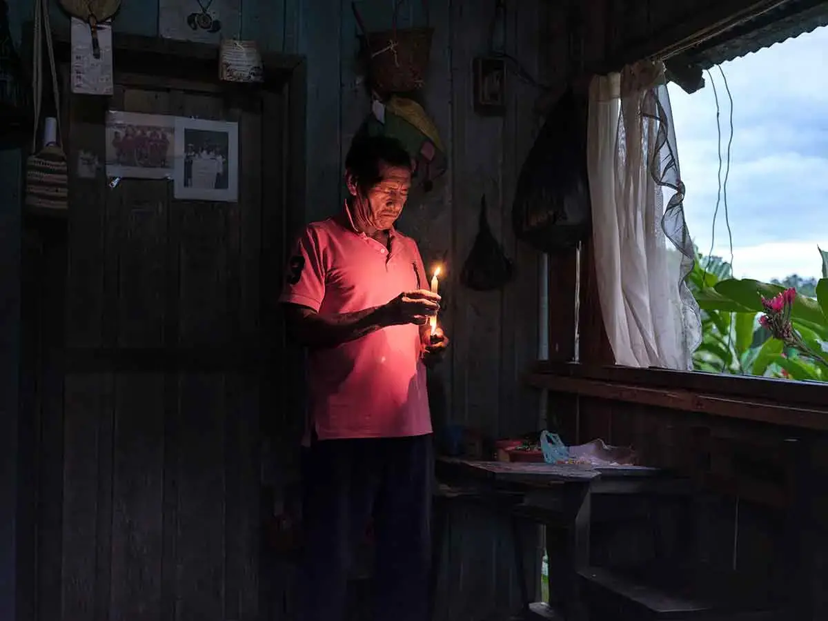 An older man lights a candle