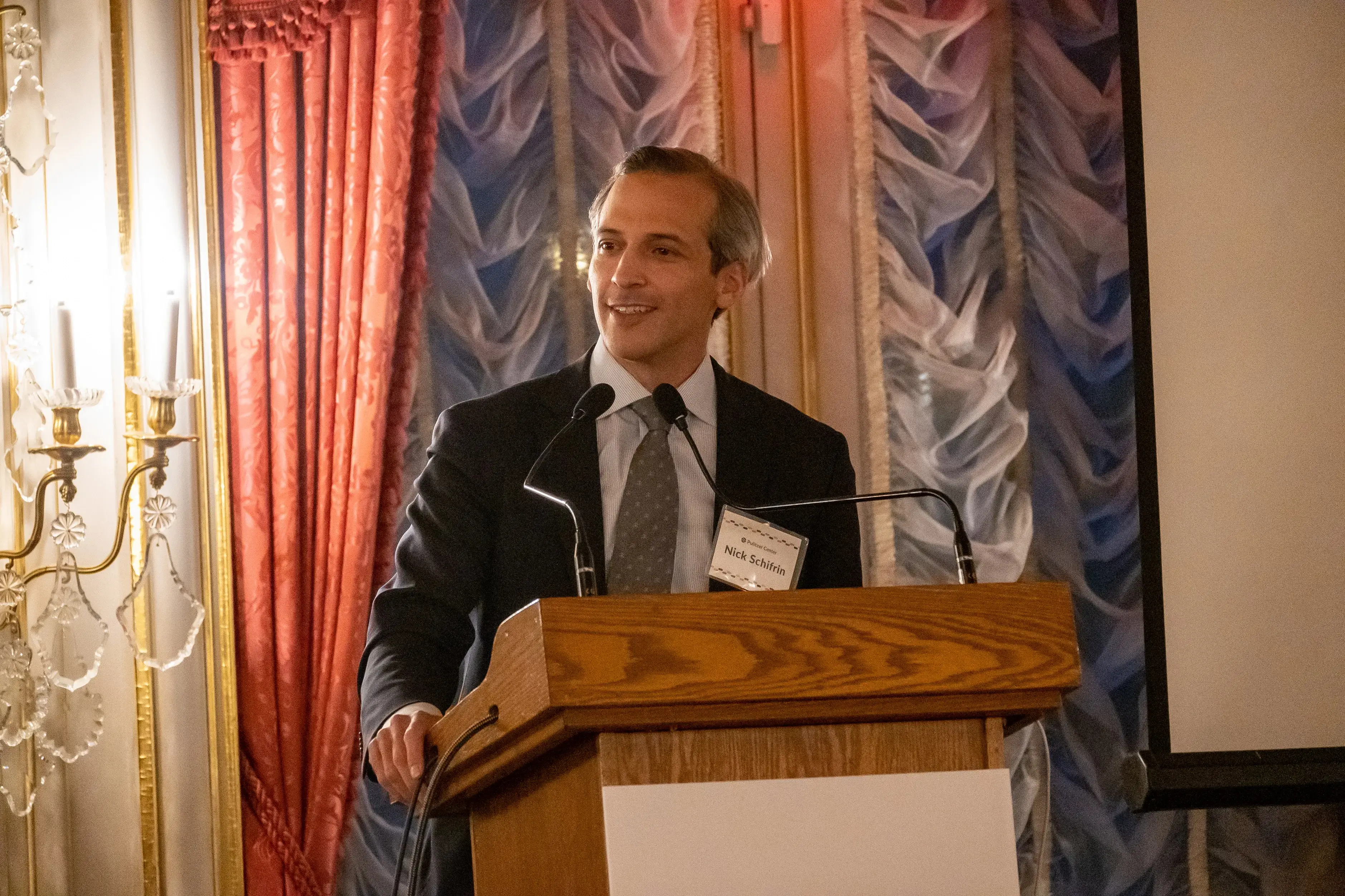 Nick Schifrin speaks at a podium at the farewell dinner at the Cosmos Club