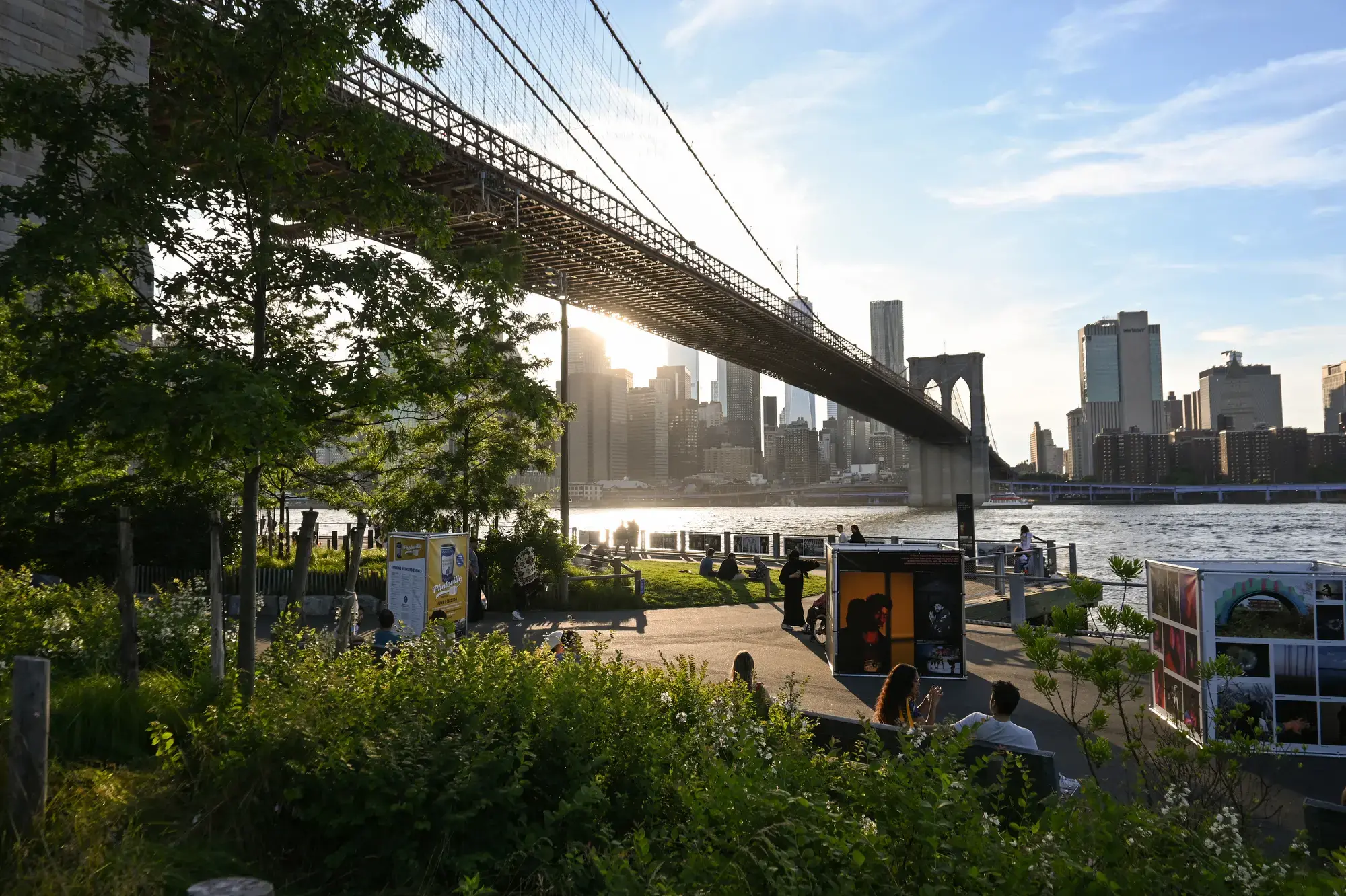 A view of Photoville exhibits underneath Brooklyn Bridge from Emily Warren Roebling Plaza in Brooklyn Bridge Park. Photo by Grace Jensen. United States, 2024. 