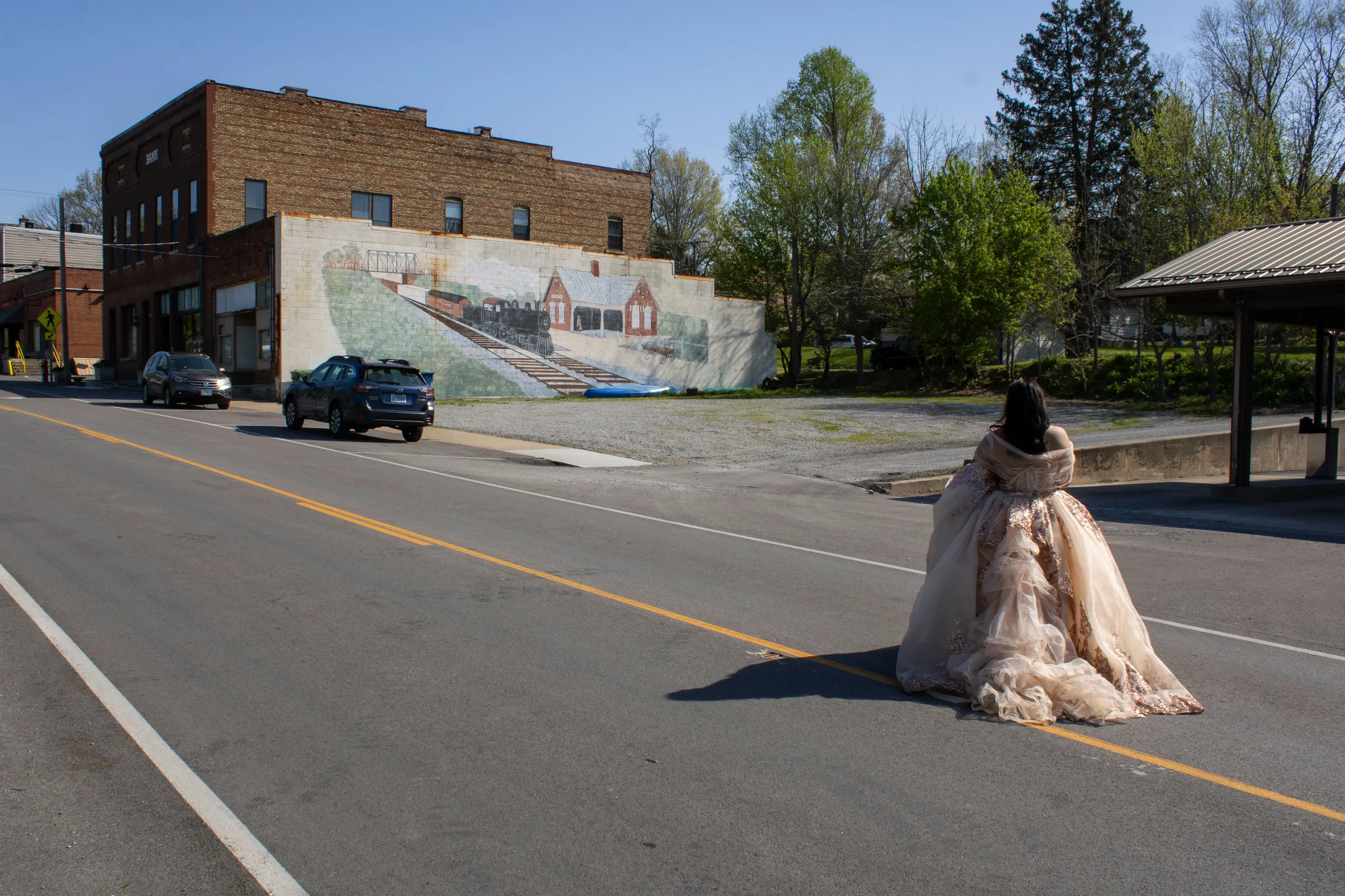A person in a flowing dress walks across a street