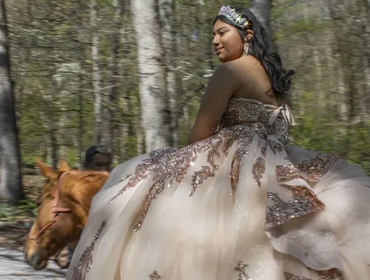 A person in a light pink gown riding a horse