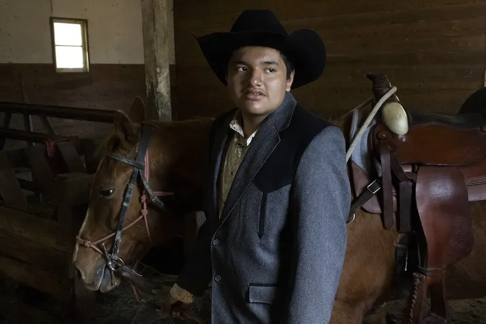 A young person in a gray blazer standing in front of a horse