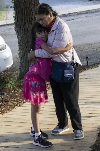 A young person in a dress hugs an older person