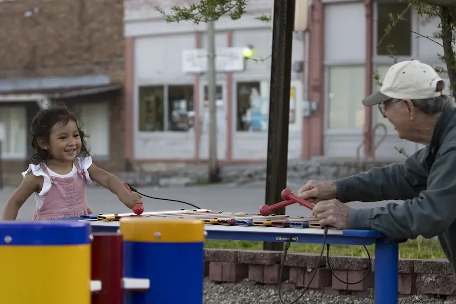 A young kid plays a xylophone with an older person