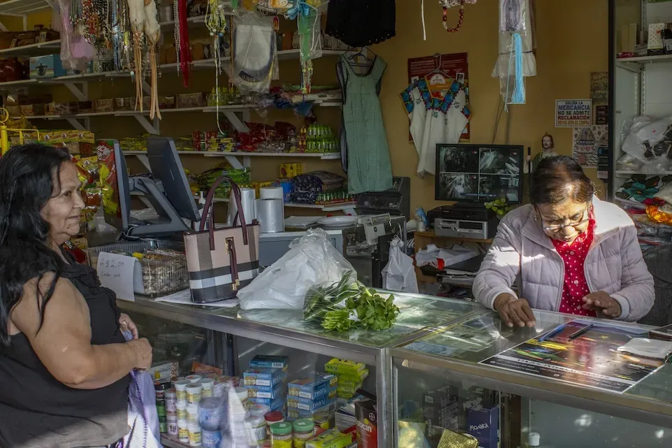 Two people stand beside a glass convenience store counter