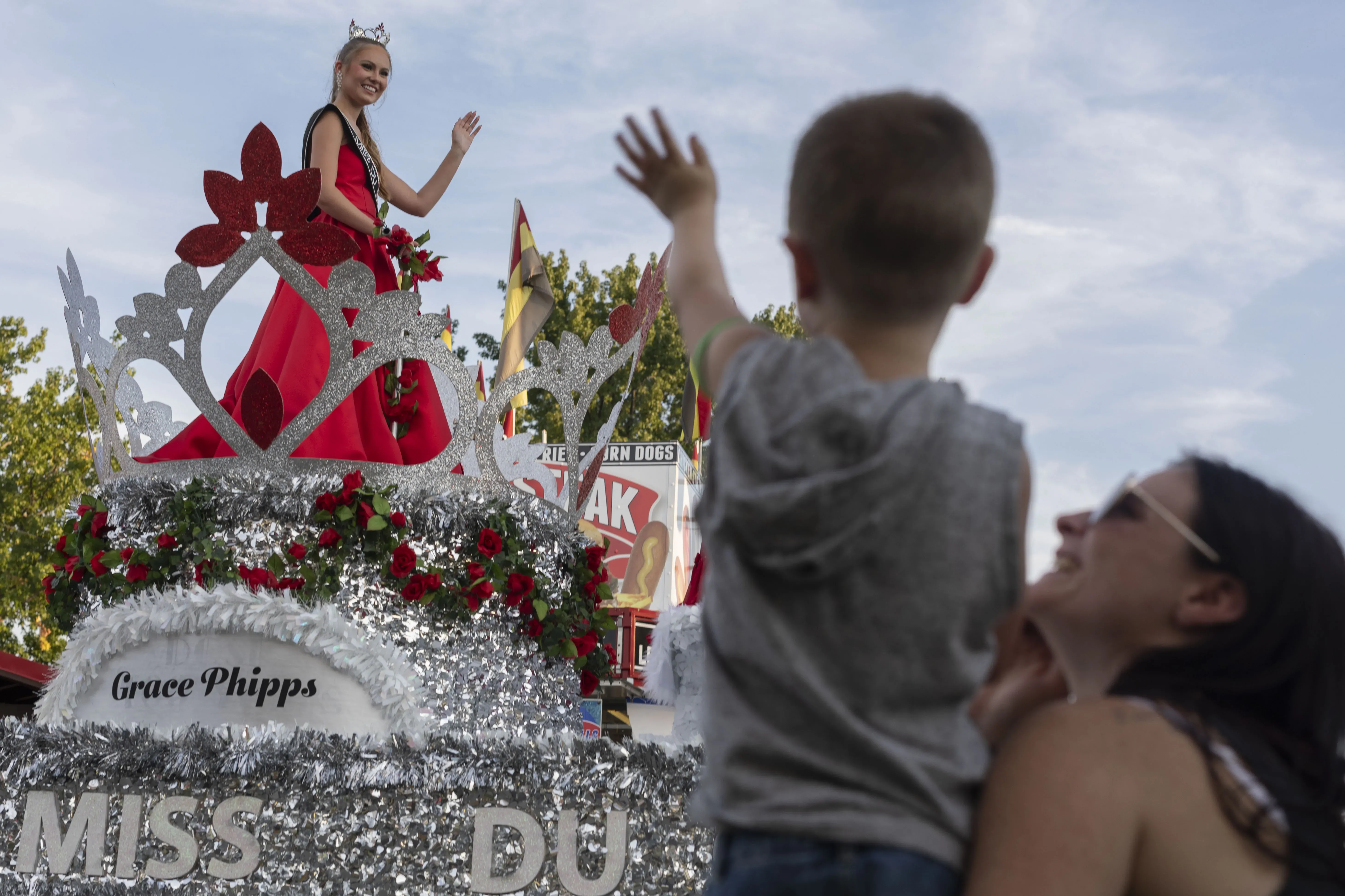 A child waves to a person on a parade float.