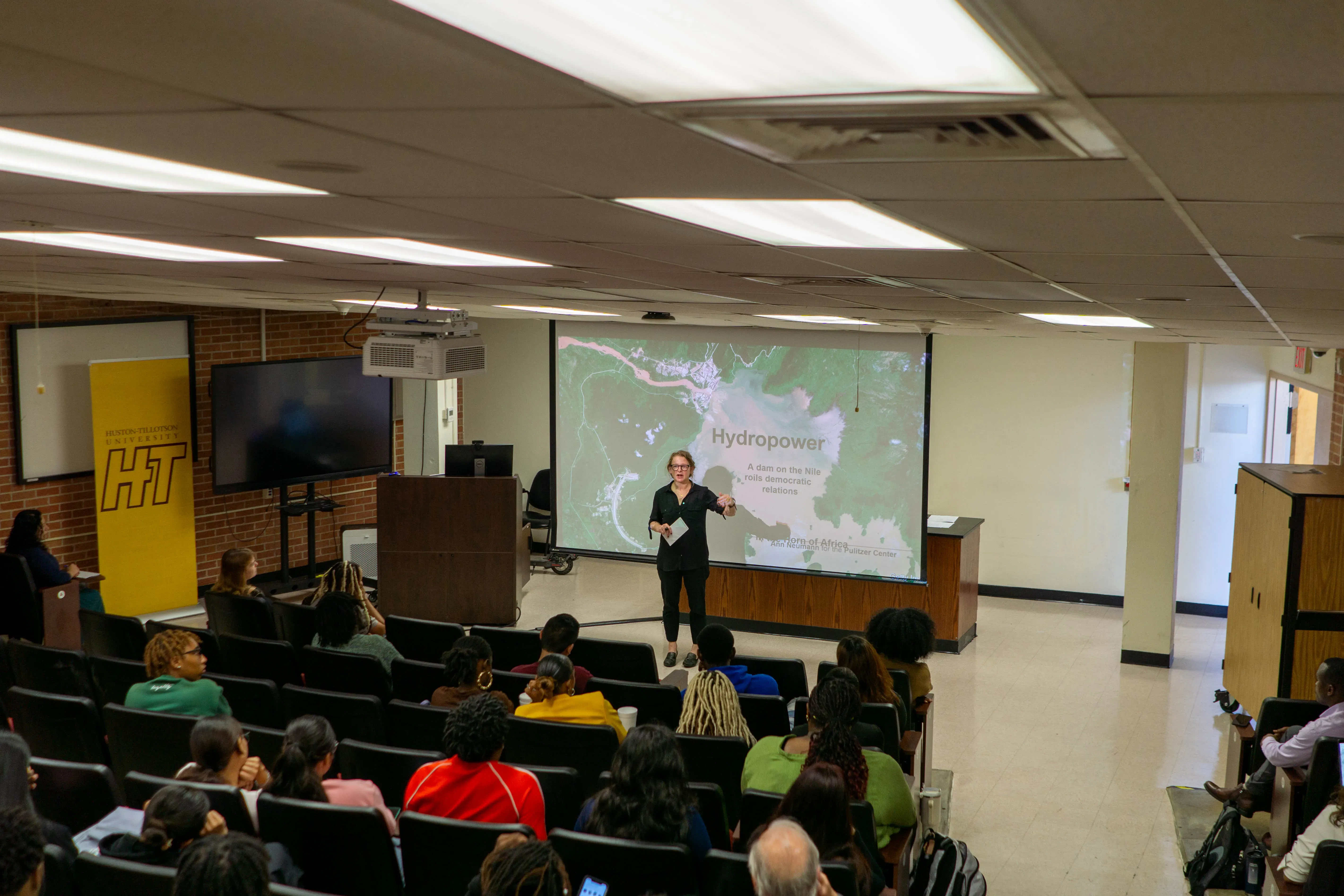 A woman speaks in front of an audience of students