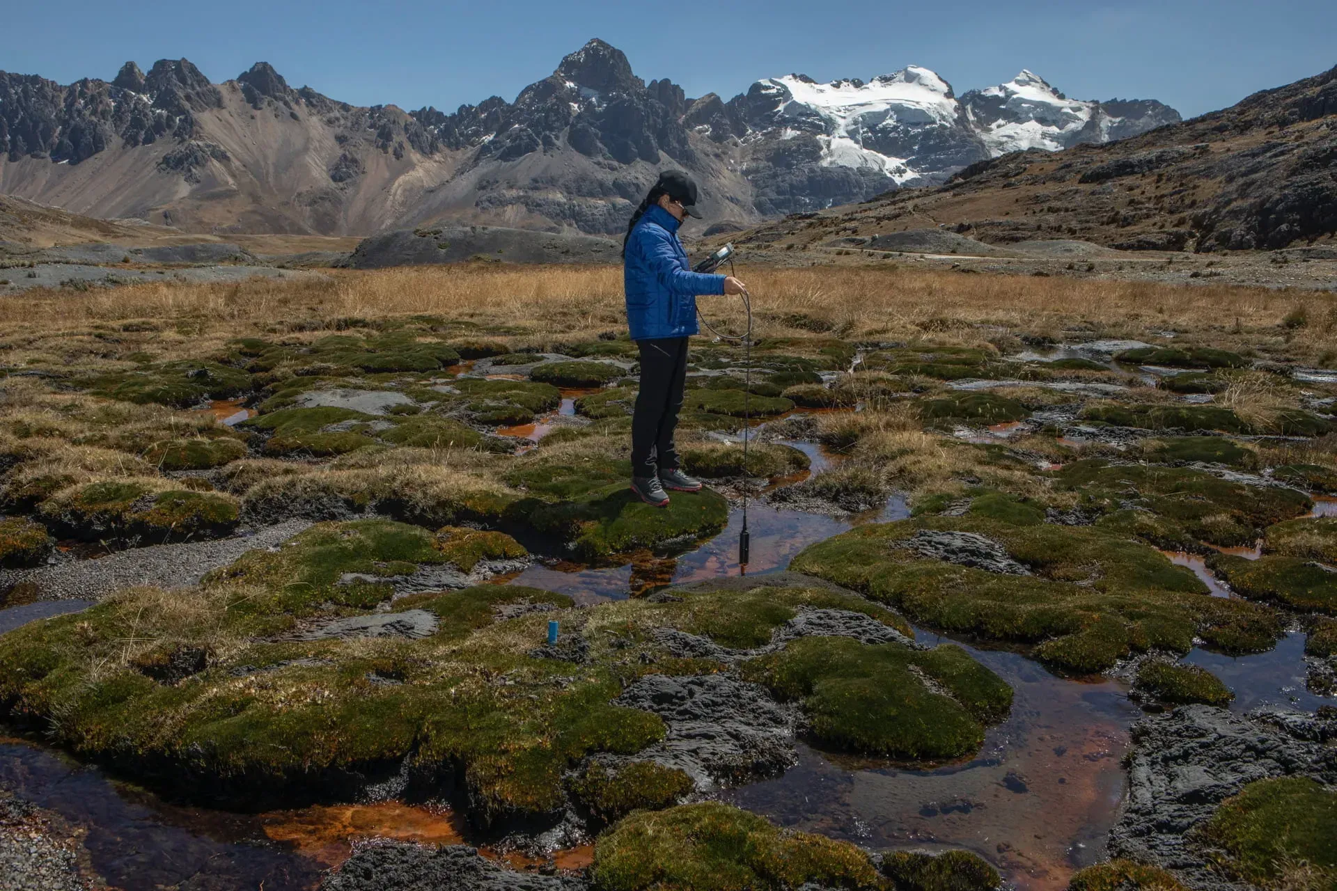 A scientist with Peru’s National Institute of Glacier and Mountain Ecosystem Research, Inaigem, dips a monitoring device into wetlands below the Pastoruri peak in the Cordillera Blanca Mountain range