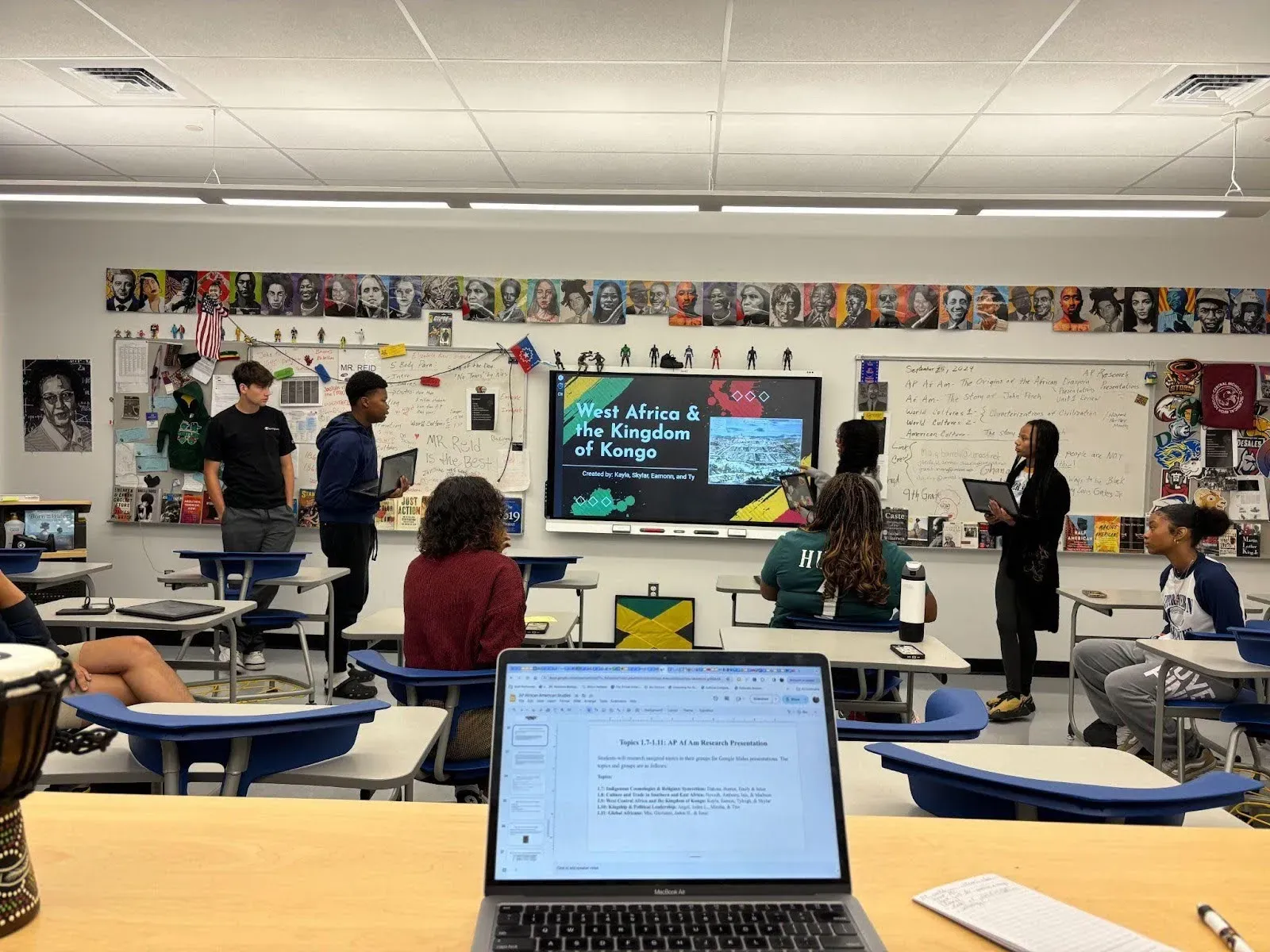 Students in an AP African American Studies class present a unit project on West Africa and Kingdom of Kongo to classmates seated at desks. 