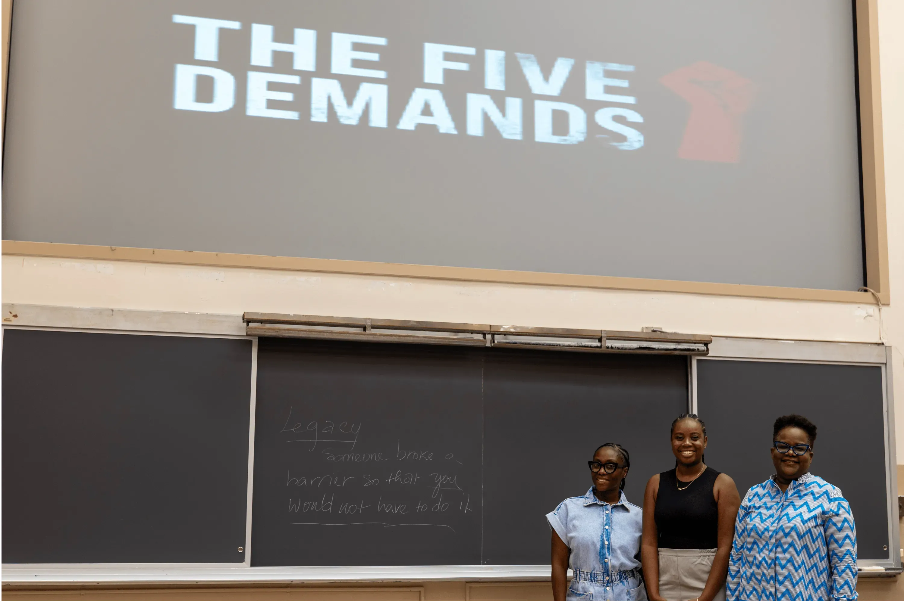 A photo of three SEEK Program facilitators in front of blackboard that reads "Legacy: Someone broke a barrier so that you would not have to." 