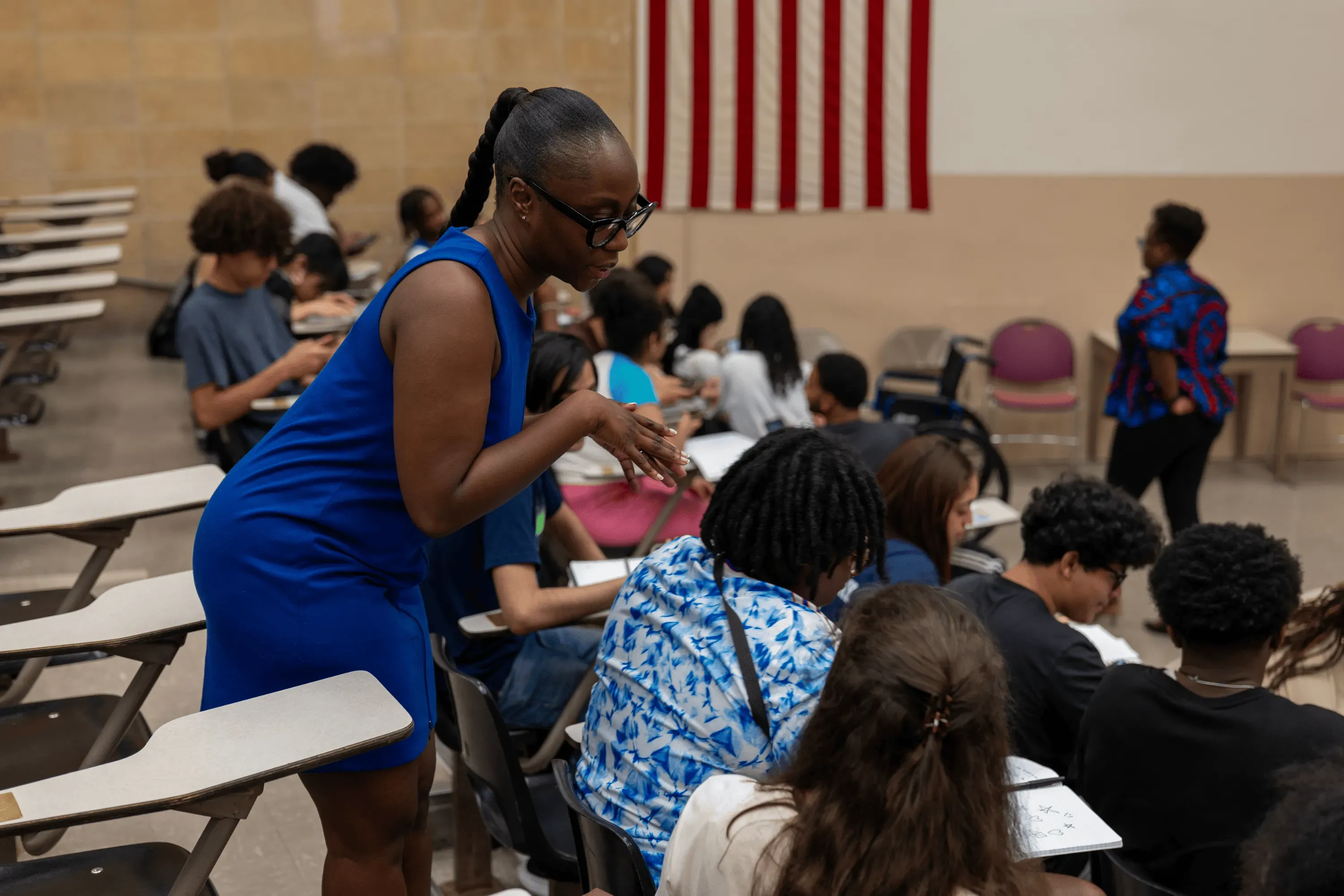 A photo of Kayla assisting students in the lecture hall during a SEEK Program course. 
