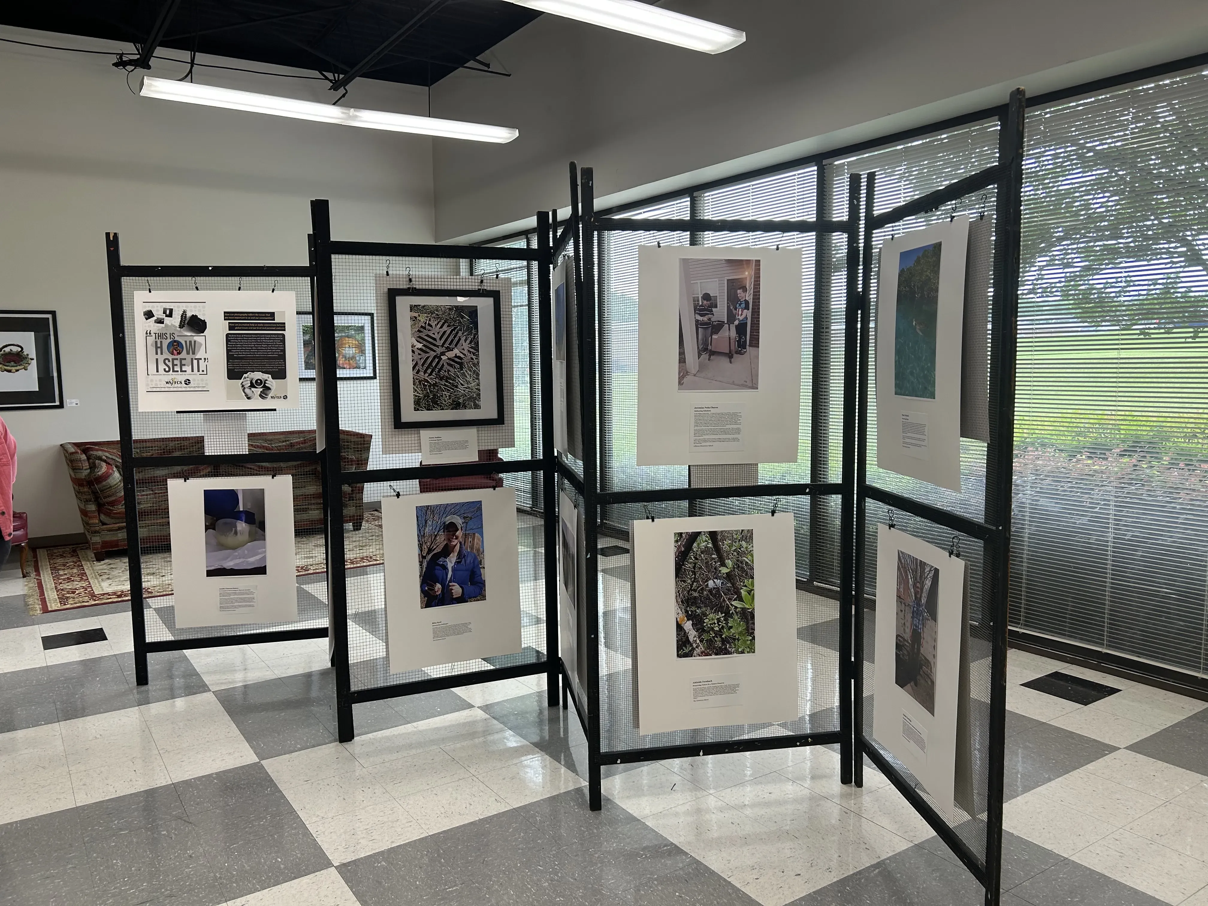 Large wire frames hold student photos for the How I See It Exhibition. Each photo is accompanied by an artist statement