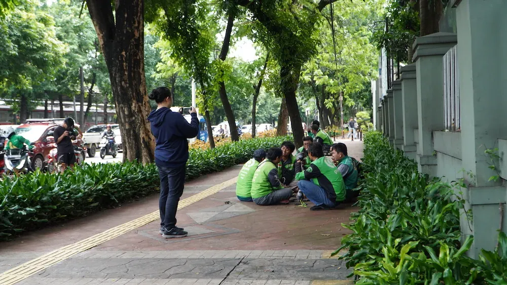 A group of ride-hailing drivers (ojol) wait for incoming orders on the sidewalk near Margonda Raya, Depok, on December 11th.