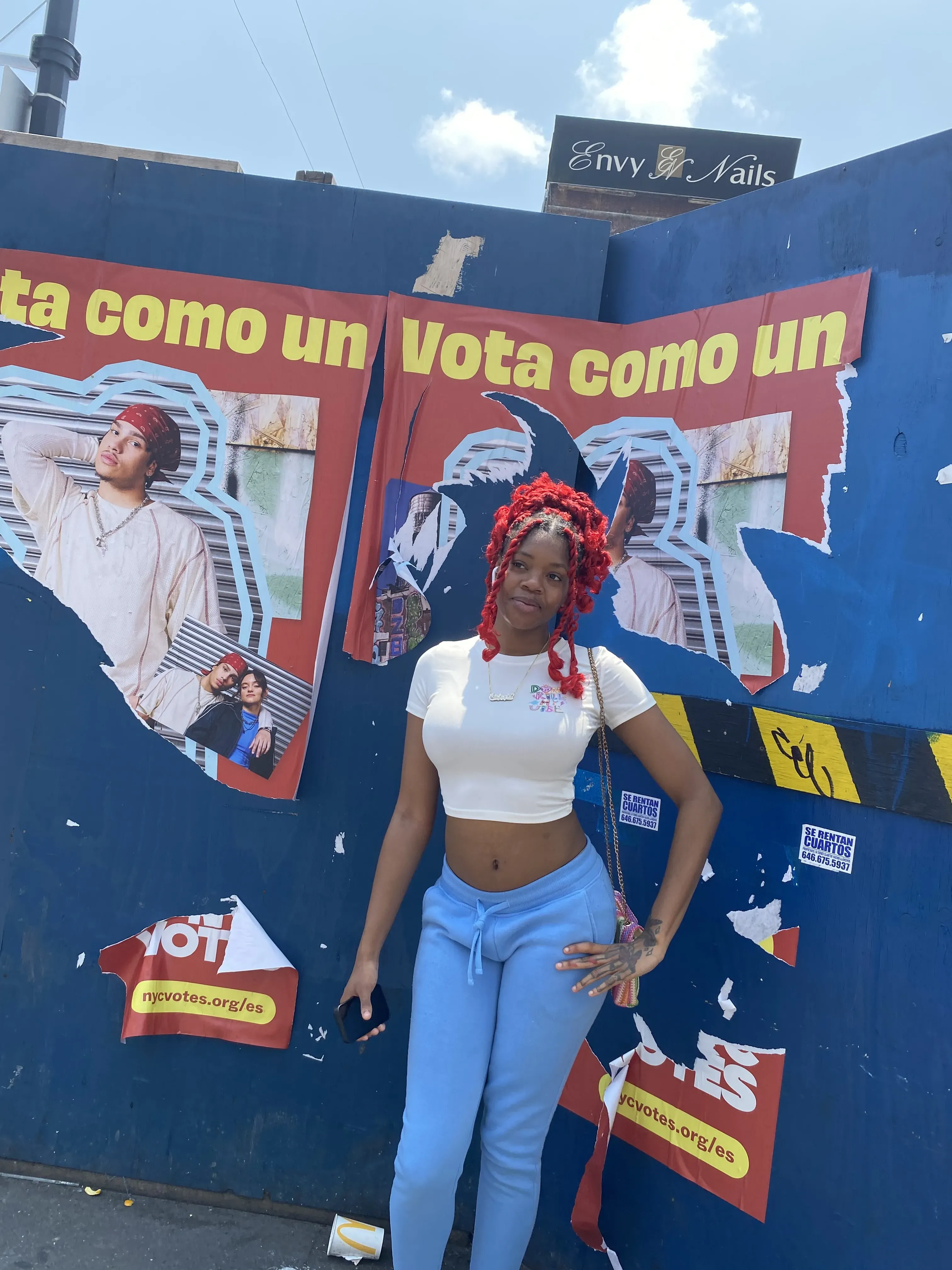 Woman in white shirt with red hair poses in front of red poster