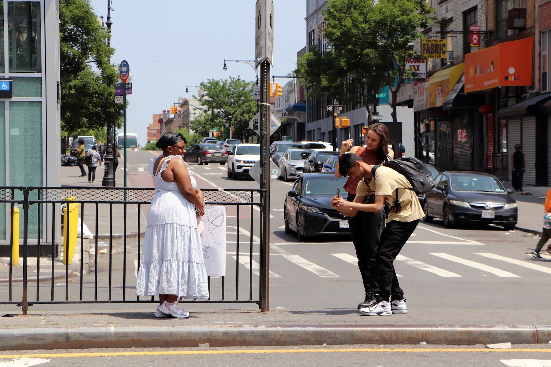 Two people take a photo of a girl posing in a street median
