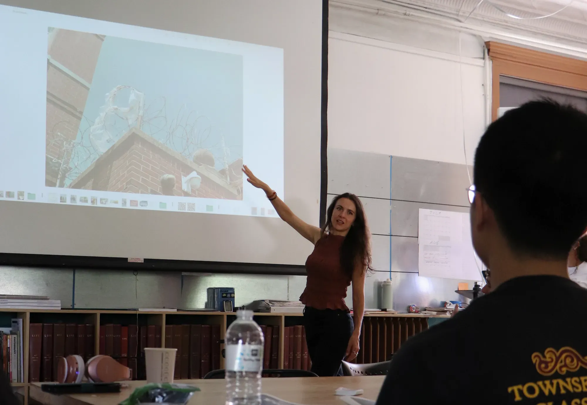 Woman gestures to screen with photo of barbed wire