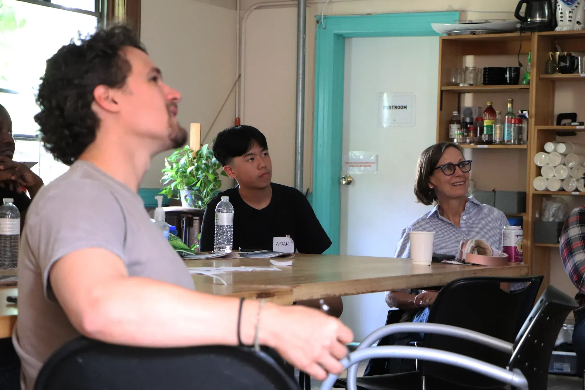 Three people look up at screen in classroom.