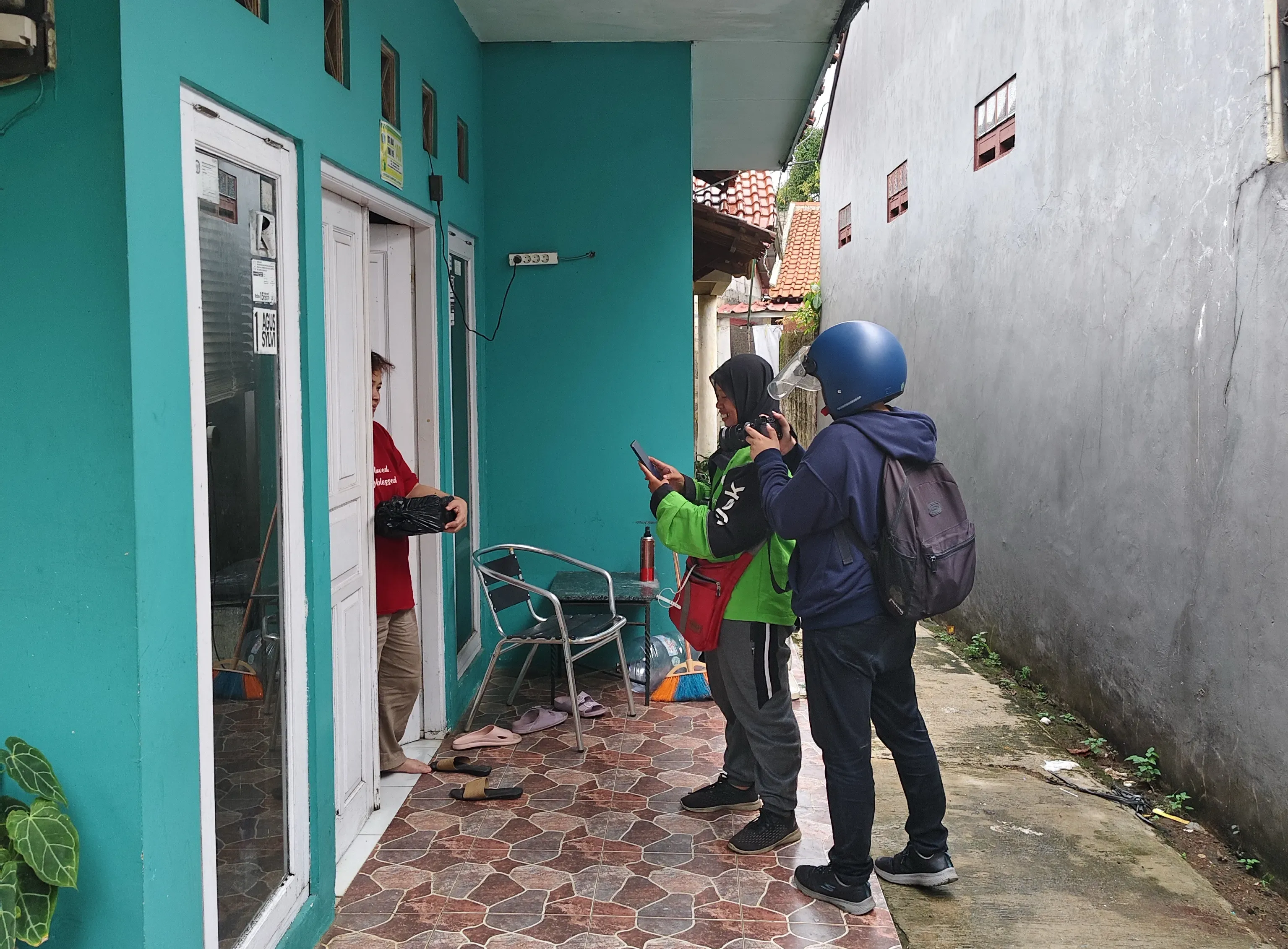 Sherlina records a video of the source delivering an order to a customer's doorstep in Srengseng Sawah, South Jakarta, on December 6th, 2024.
