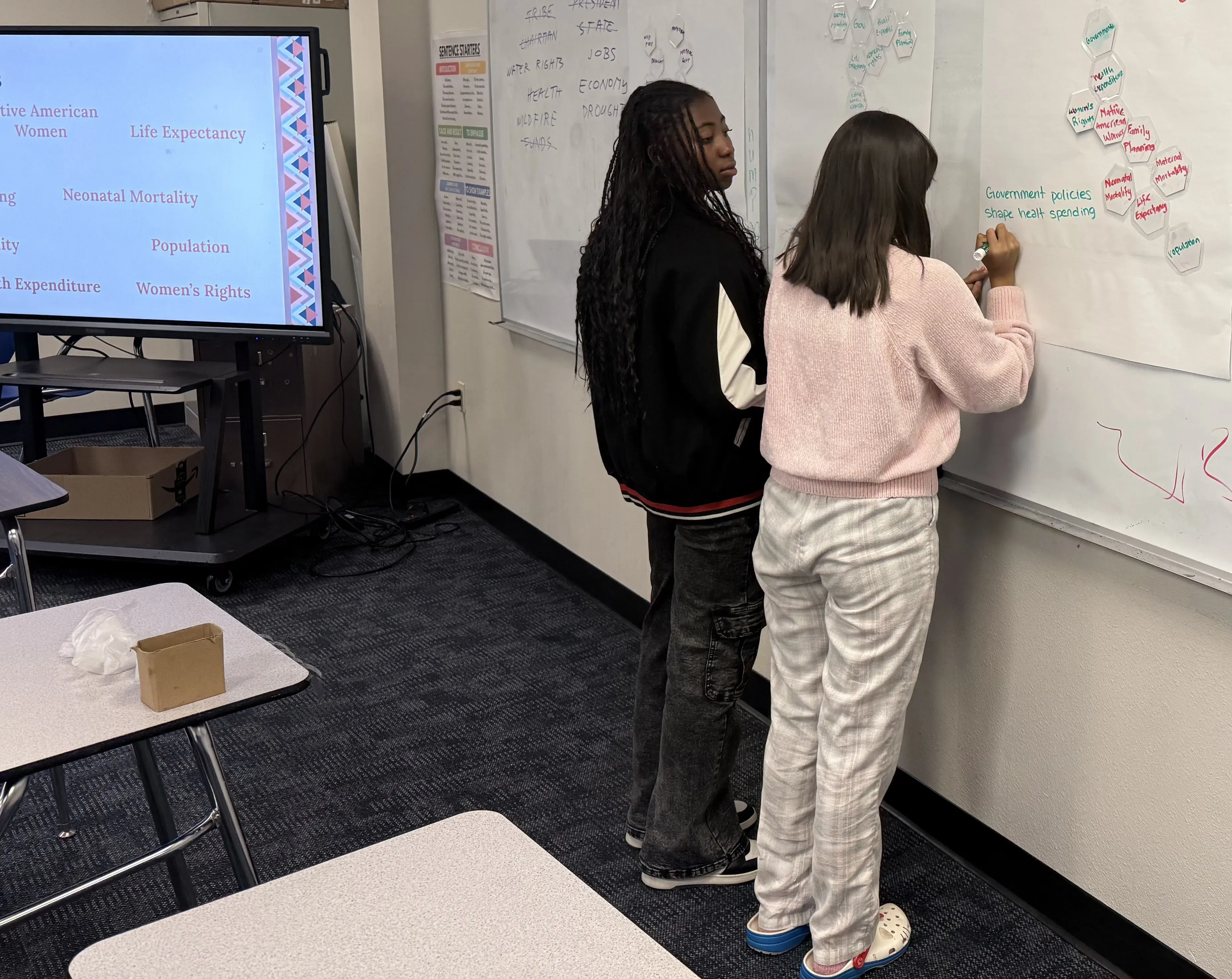 two students writing on white board