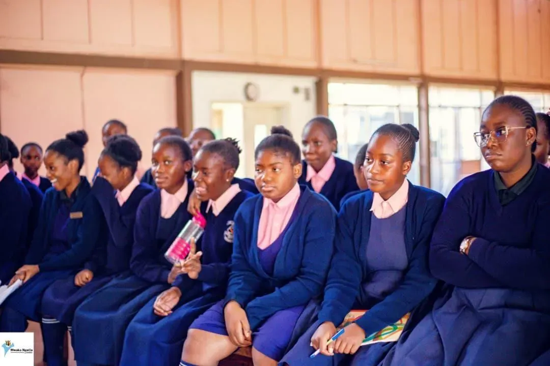 Female students sit in an assembly. 