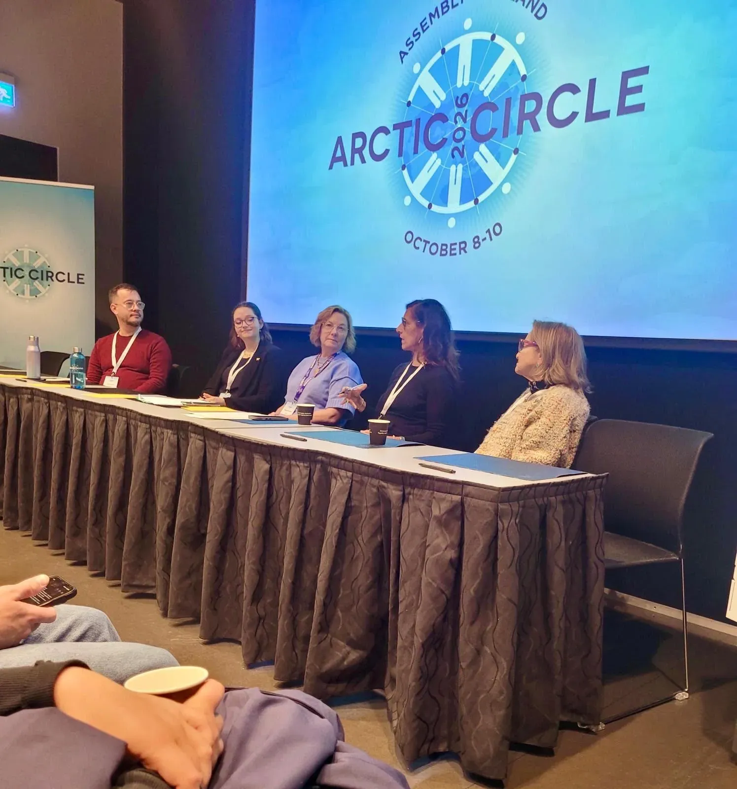 panelists sit at a table in front of a projection that says "Arctic Circle"