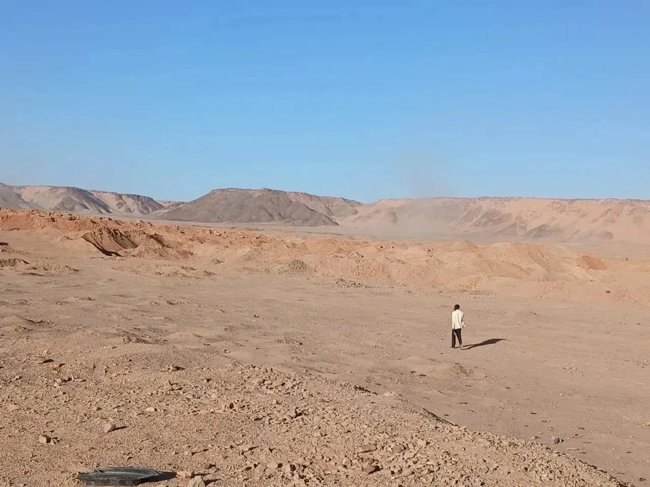 Djado, Niger. A man walks toward excavated pits at a mining site. Image by Amma Moussa.