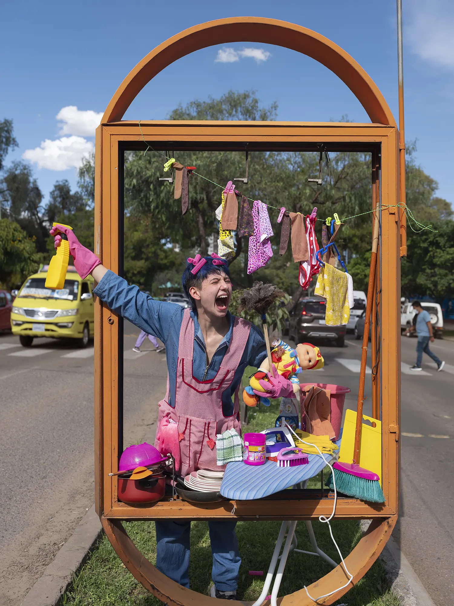 Tam stands holding items that represent women's roles in and out of the home in Bolivia 