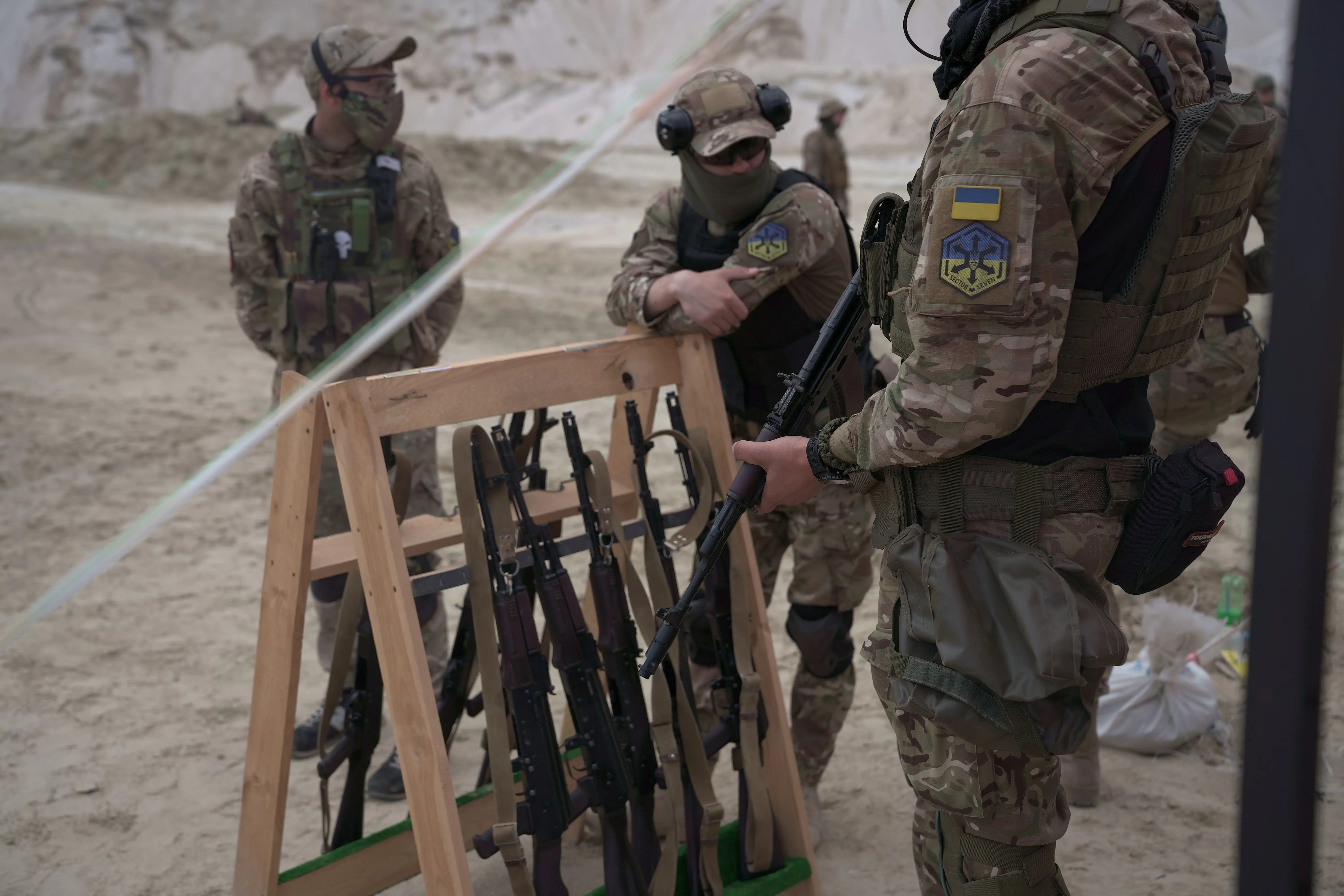 A group of soldiers stand by a stand of rifles