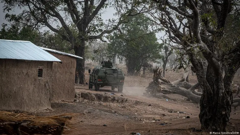 A military Humvee kicks up dust along a village road.