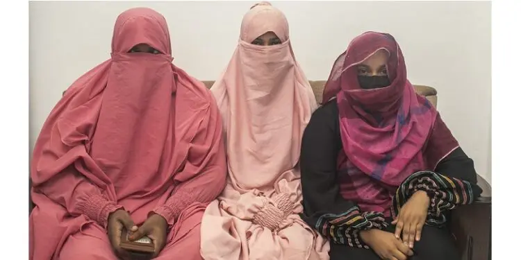 Three women sit together on a couch