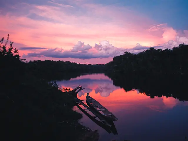 Sunset creates pink and purple skies reflected in a river.