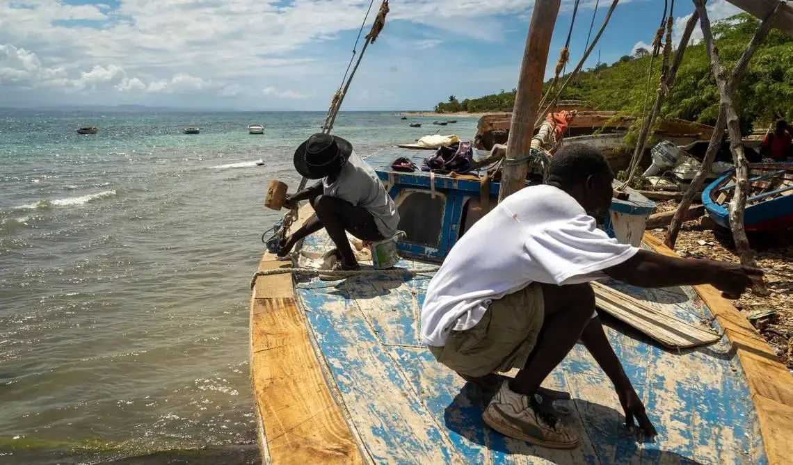 Two men work on building a sailboat together 