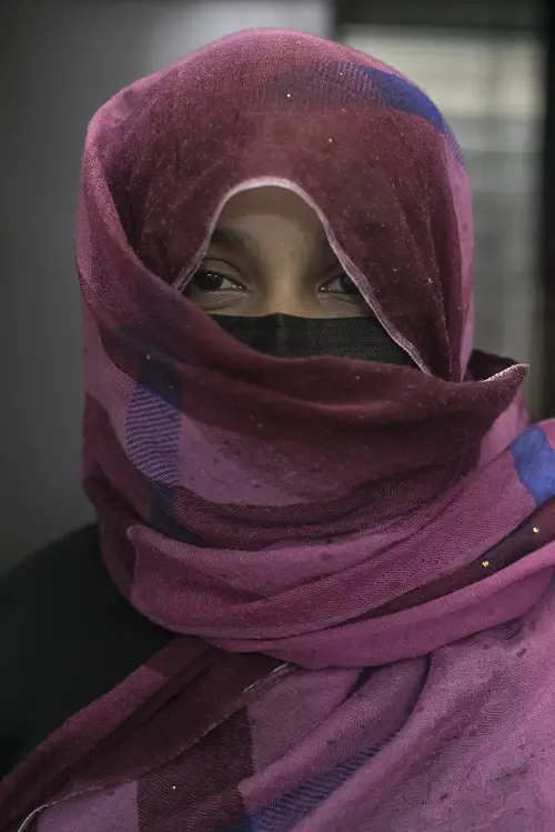 A woman masked and in hijab poses for a photo