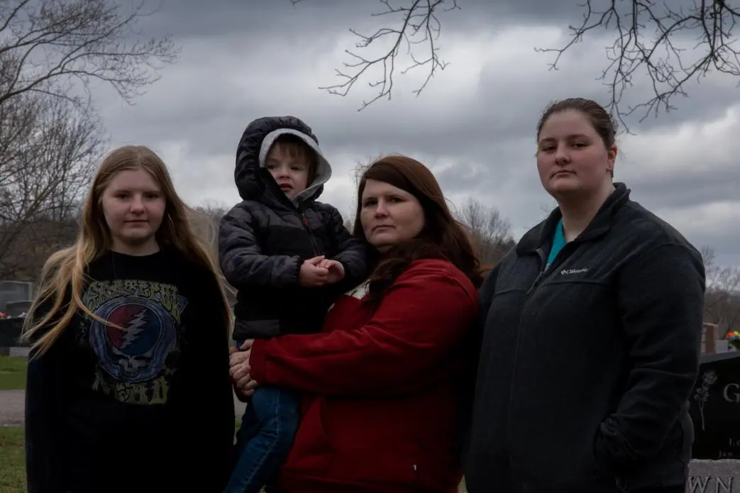 A family stands for a portrait with grim faces.