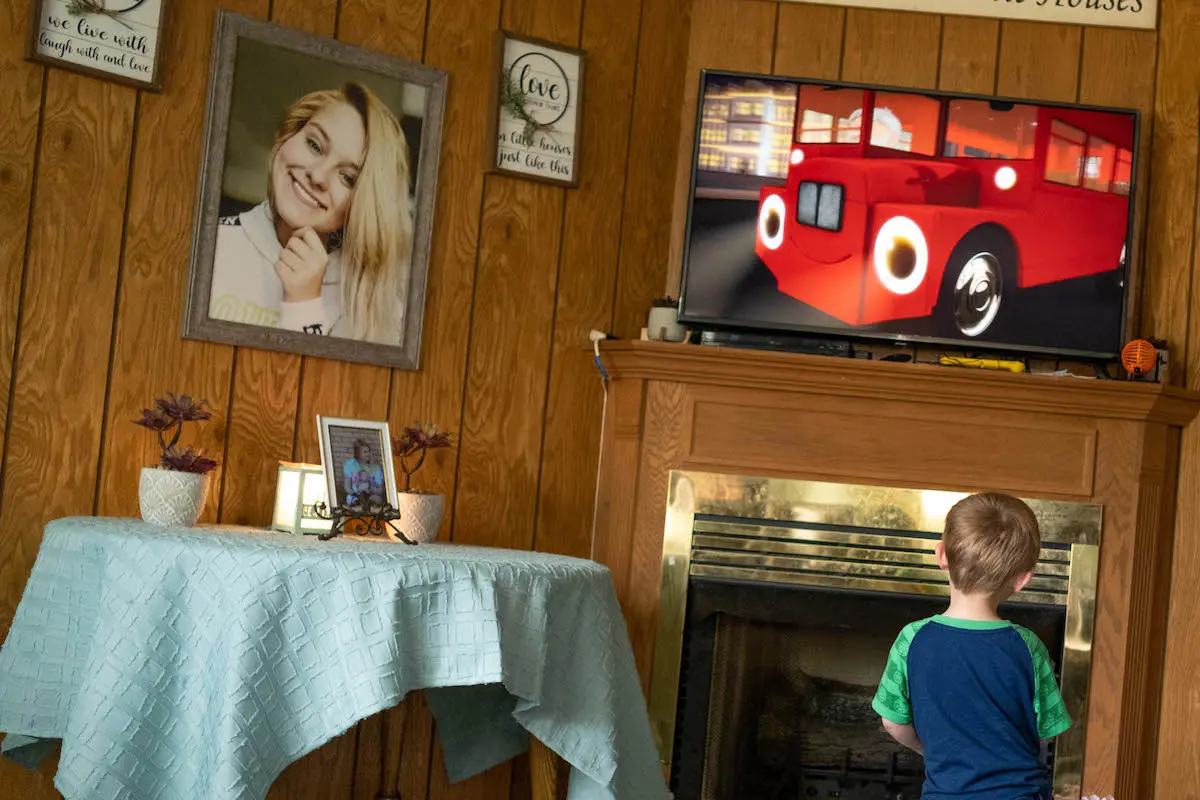 Aaron watches television where a picture of Rodgers hangs