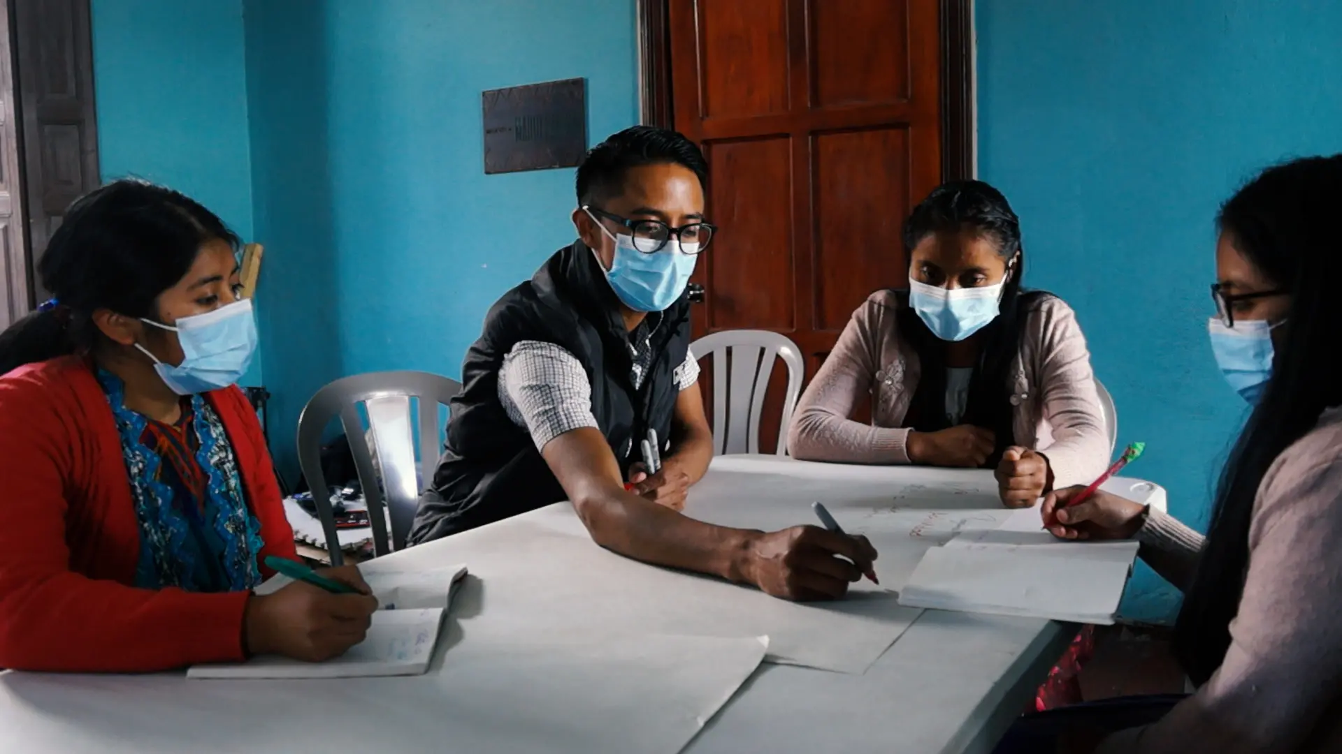 Santos Istazuy Pérez (second left) writes on a poster