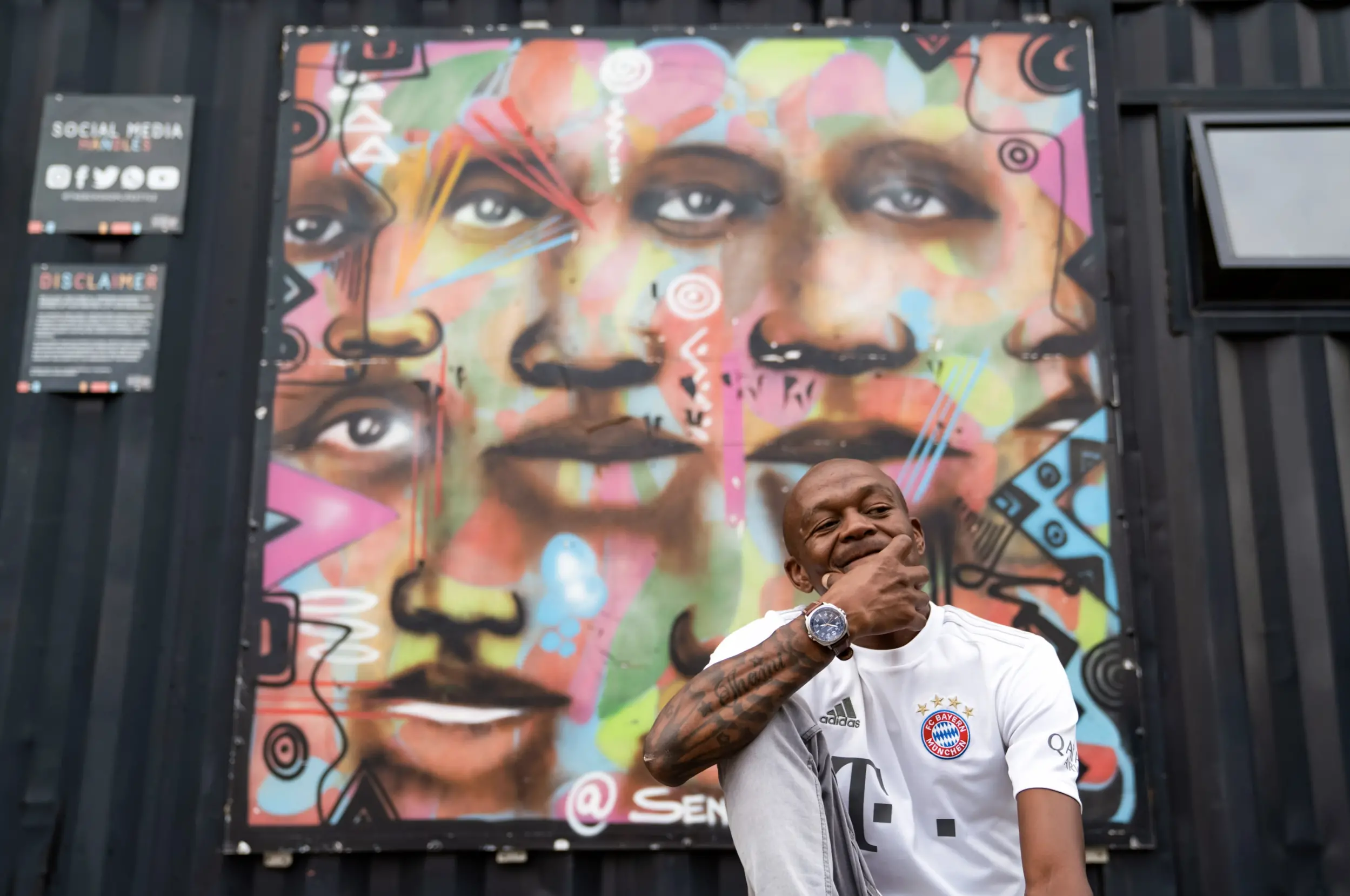 Man sits in front of mural