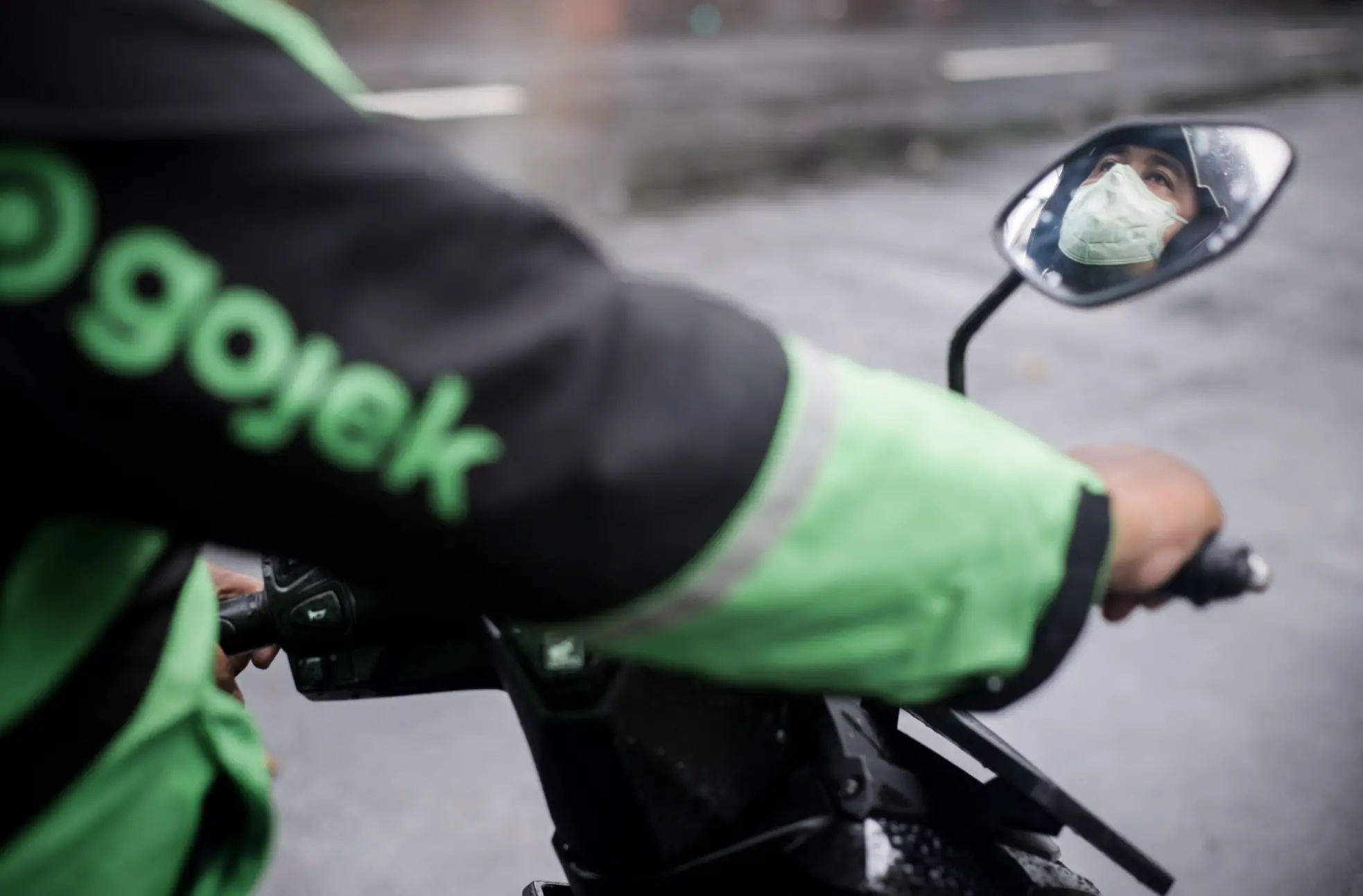 A man is shown wearing a mask under his helmet on a delivery scooter