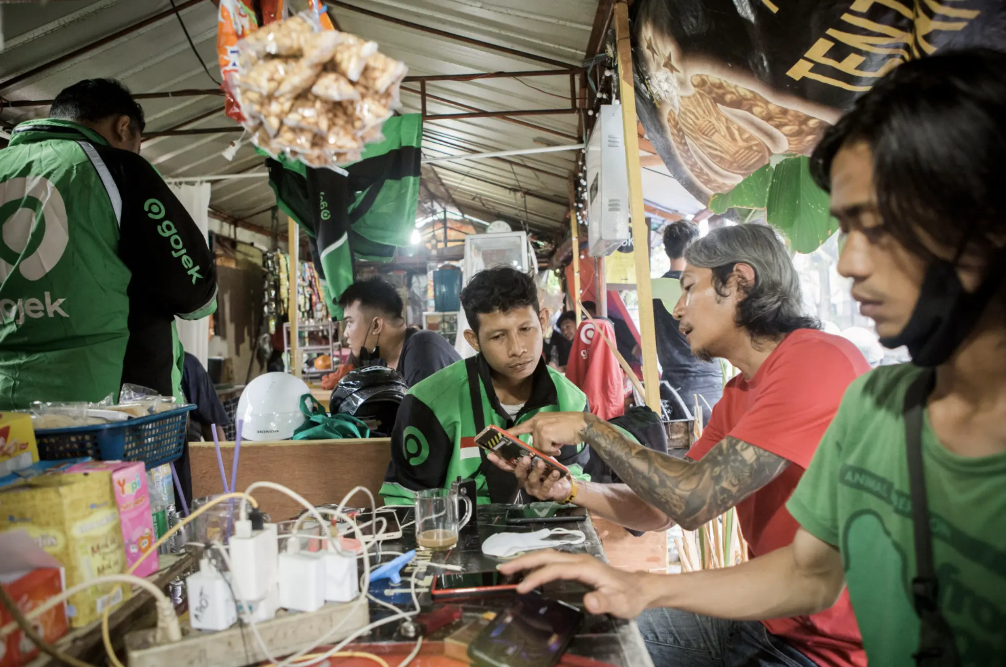 A man shows another man something on his phone in a roadside stall 