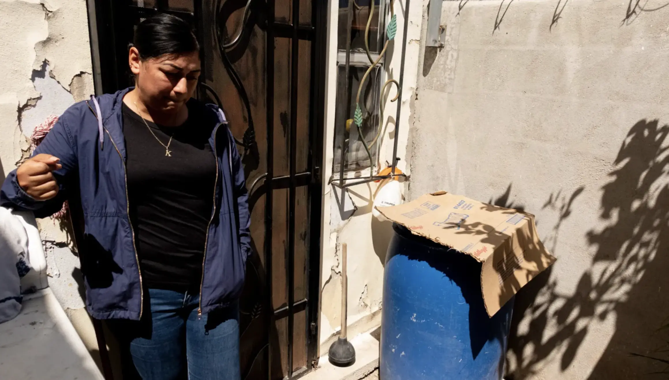 A woman shows her blue tub that stores her water